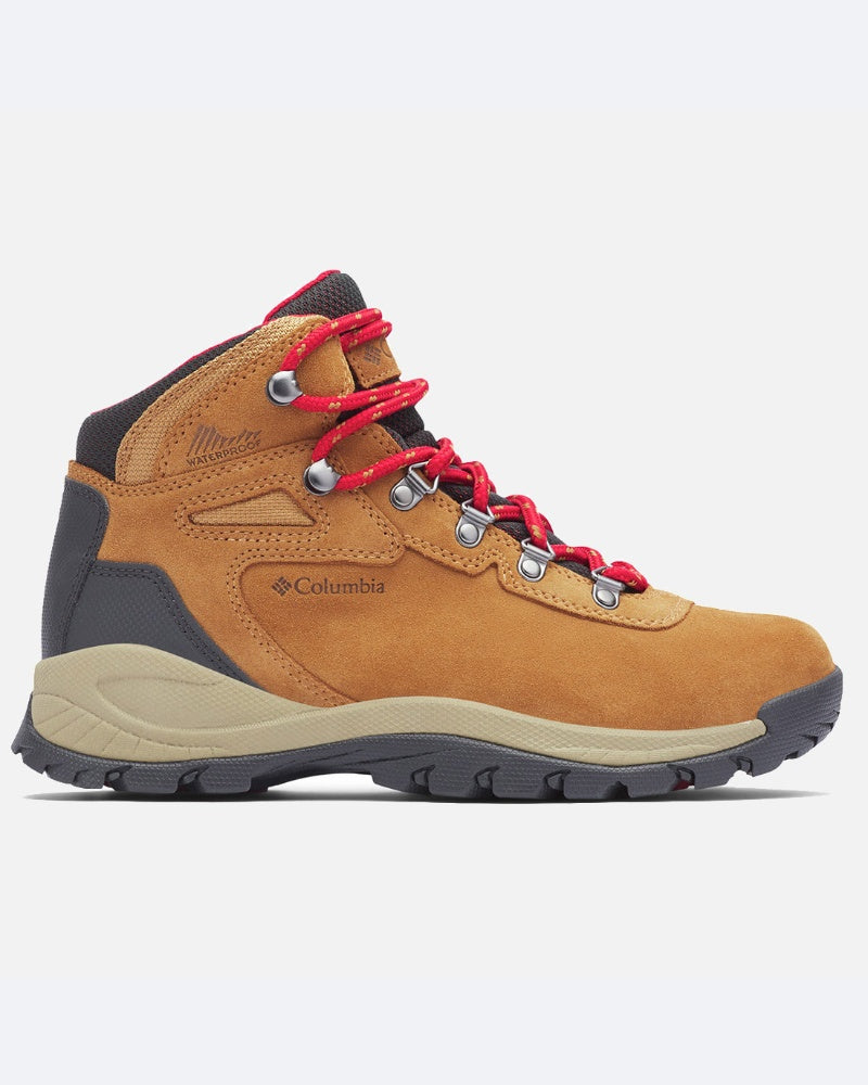 מגף הטיולים ColumbiaIL Newton Ridge Plus Waterproof כולל חלק עליון בצבע חום בהיר, נגיעות בצבע אפור כהה, שרוכים אדומים, לולאות מתכת וסוליה שחורה/אפורה ועמידה, המוצג בפרופיל צדדי על רקע בהיר.