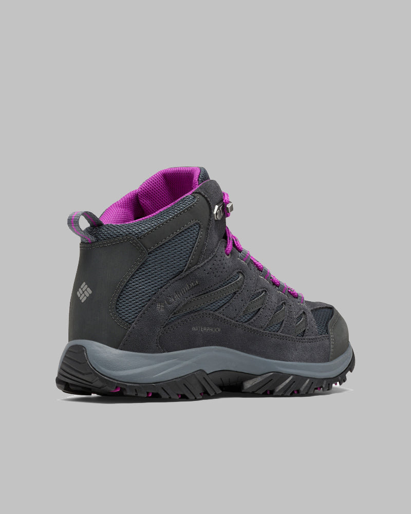 מגפי הטיולים ColumbiaIL Crestwood Mid Waterproof W, המוצגים בצבע אפור כהה עם שרוכים, בטנה ודפוס סוליה סגולים על רקע אפור, מתאפיינים בסוליה עמידה ובעיצוב המגיע עד הקרסול, המושלם לנשים.