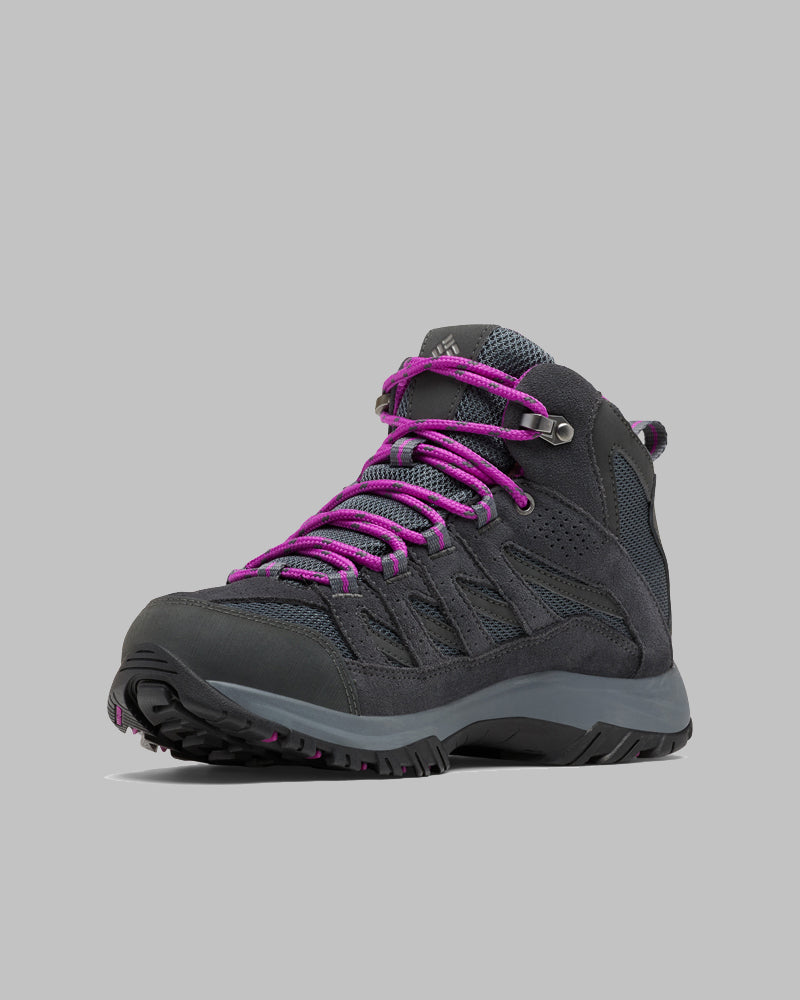 ה-ColumbiaIL Crestwood Mid Waterproof W הוא מגף נשים בצבע אפור כהה עם סוליה עבה ושרוכים סגולים, המוצג בזווית על רקע אפור אחיד — מגפי טיולים אטומים למים, אידיאליים לכל הרפתקה בטבע.