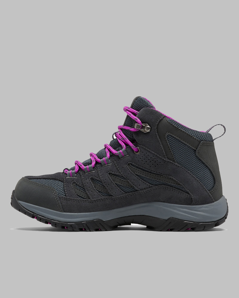ה-ColumbiaIL Crestwood Mid Waterproof W הוא מגף טיולים בצבע אפור כהה עם לוחות רשת שחורים, נגיעות סגולות ושרוכים סגולים בוהקים, המוצג בפרופיל צדדי על רקע אפור אחיד.