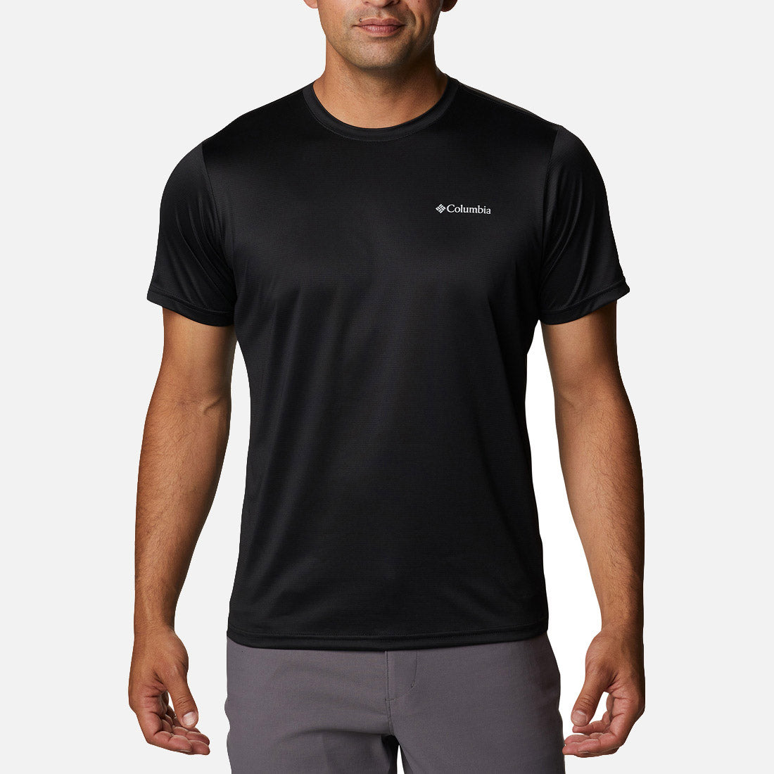 A man in a Columbia Hike Crew Black short-sleeve T-shirt and gray pants stands facing forward against a white background, with the Columbia logo displayed on the left chest.