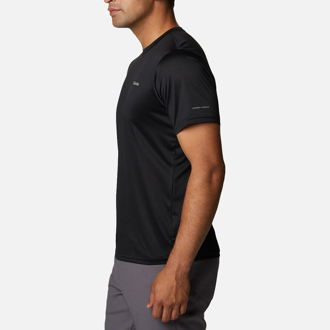 Side view of a man wearing the Columbia Hike Crew Black t-shirt with Omni-Wick on the sleeve, paired with gray pants.