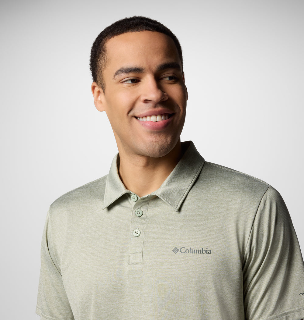 גבר לבוש בחולצת פולו "קולומביה ישראל Columbia Hike Polo" בצבע ירוק בהיר מחייך תוך שהוא מביט שמאלה, על רקע אפור בהיר אחיד.
