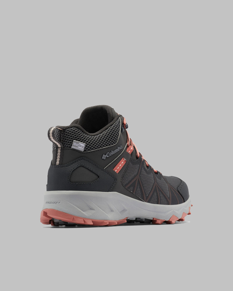 מגף טיולים לנשים מדגם ColumbiaIL Peakfreak II Mid Outdry W בצבעי שחור ואפור עם נגיעות אדומות מוצג בזווית על רקע אפור אחיד, עם סוליות מחוספסות ופרטי רשת סביב הקרסול.