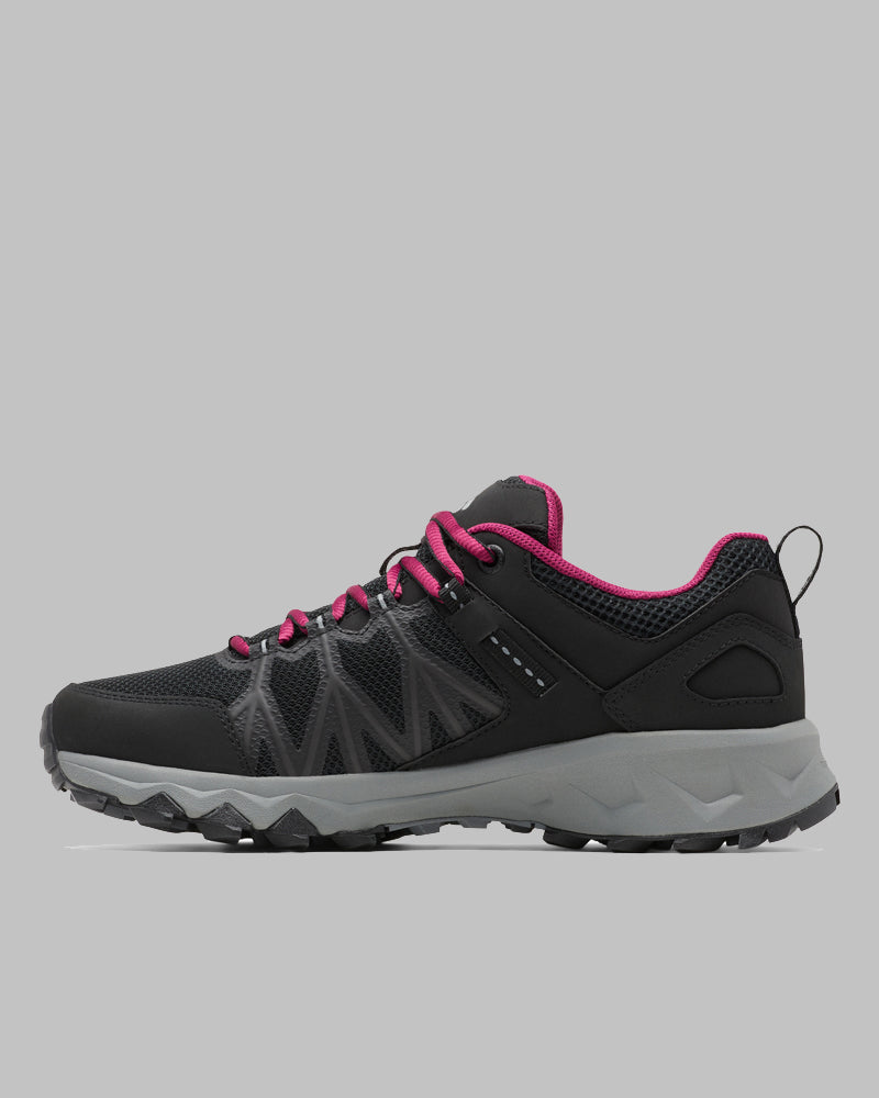 ה-Peakfreak II Outdry W של ColumbiaIL היא נעל טיולים לנשים בצבע שחור, עם סוליה אפור עבה, שרוך ופרטי בטנה בצבע ורוד, וחלק עליון מרשת, המוצגת בפרופיל צדדי על רקע אפור אחיד.
