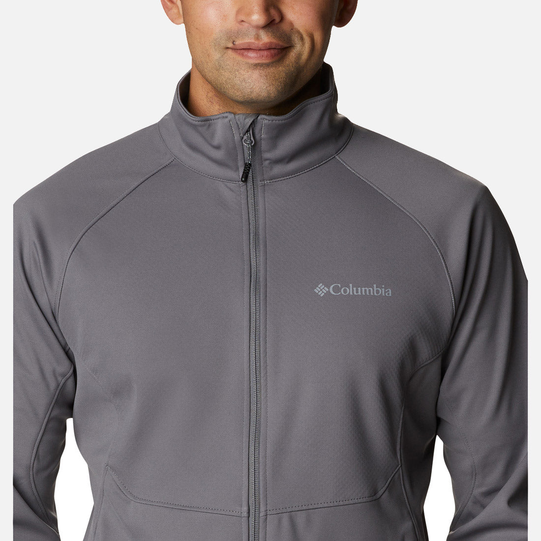 גבר לבוש במעיל קולומביה IL Canyon Meadows Softshell עם רוכסן מלא עומד פונה קדימה, ונראה מהחזה ומעלה. לוגו המותג מופיע על החזה השמאלי. הרקע לבן חלק.