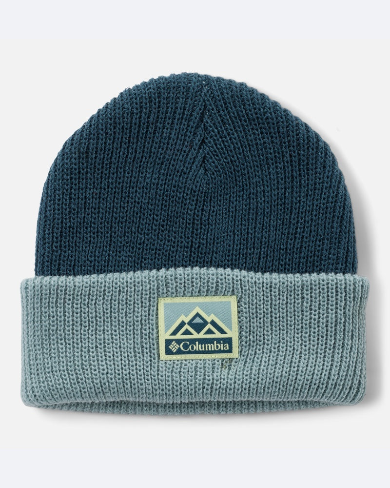 כובע ה-Whirlibird Beanie של ColumbiaIL לילדים הוא כובע חורף סרוג לילדים, בעל חלק עליון בצבע כחול כהה, שוליים מקופלים בצבע תכלת ותווית מלבנית עם לוגו Columbia בחזית — אידיאלי לימים קרירים.