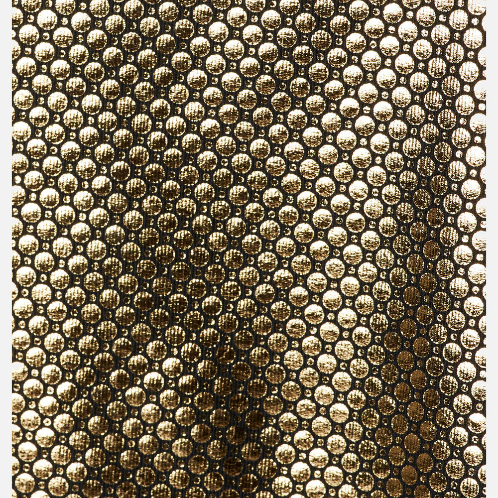 תקריב של חולצת ה-Omni-Heat Infinity Knit L/S Crew של columbiaIL W חושף את משטחה המרקם בצבע זהב מטאלי, עם דפוס חוזר של נקודות עגולות בולטות, היוצר אפקט מבריק ויוקרתי המזכיר סריגים מורכבים.