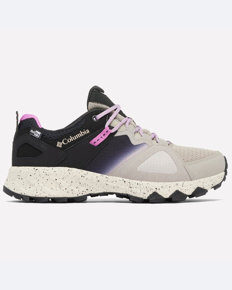 דגם Peakfreak Hera Outdry מבית columbiaIL הוא נעל ריצת שטח בצבעי בז' ושחור, עם סוליה מנוקדת, נגיעות סגולות בגוונים מדורגים ושרוכים. הנעל, העשויה מרשת וחומרים סינתטיים, בעלת עיצוב נמוך ומציעה נוחות בכל תנאי שטח.
