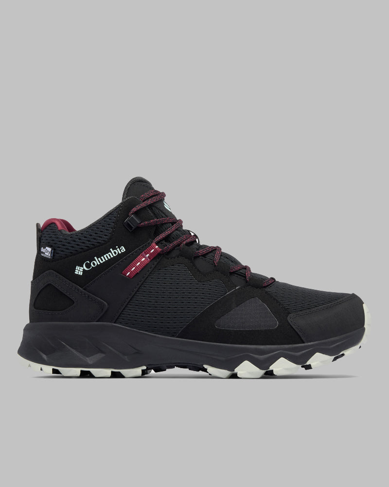 מגפי הטיולים Peakfreak Hera Mid Outdry של קולומביה ישראל, בצבע שחור, כוללים שרוכים בצבע בורדו, לוגו לבן, לוחות רשת מרקמים וסוליה עמידה בשחור-לבן, המוצגים בפרופיל על רקע אפור אחיד.