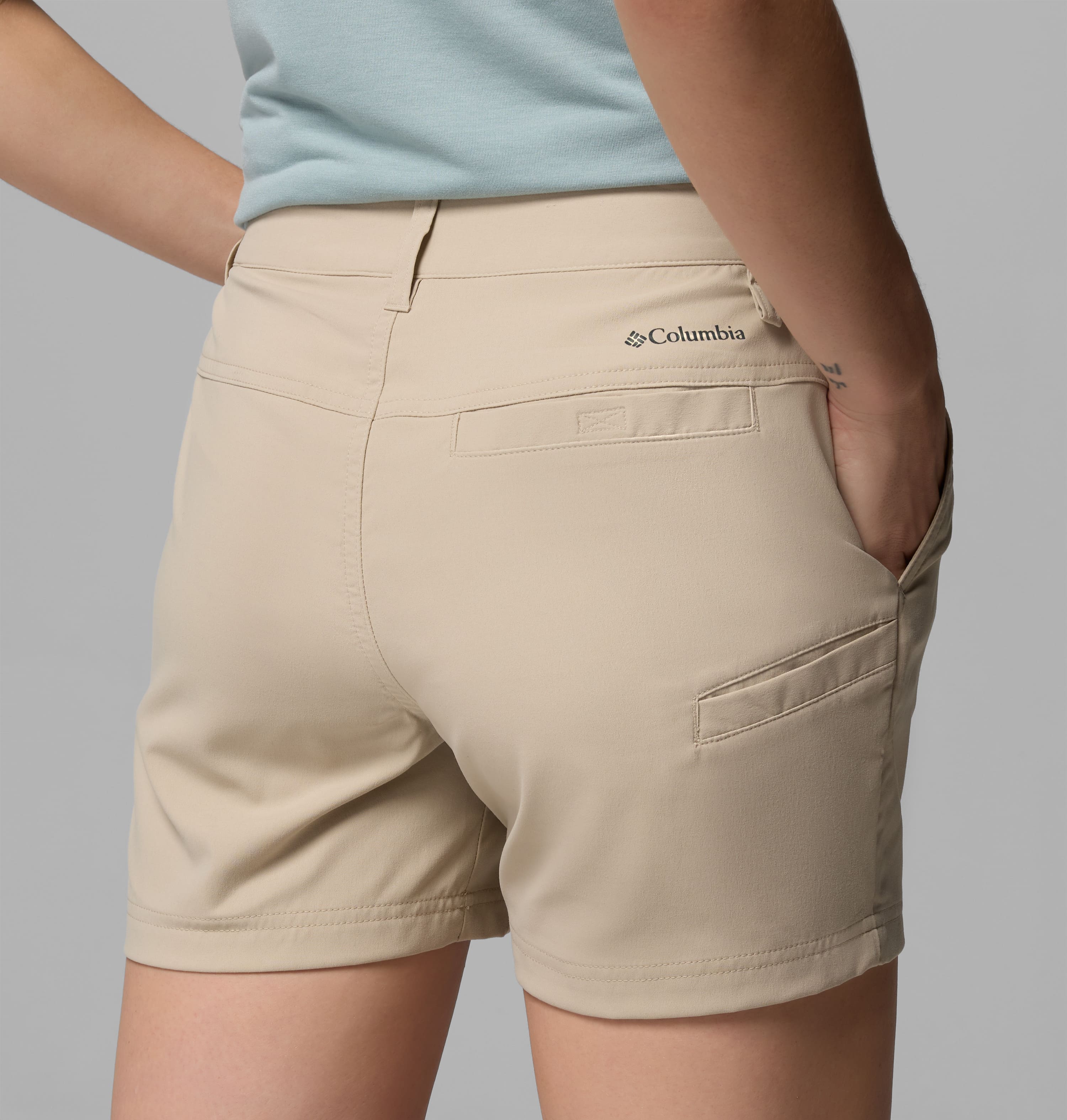 אדם הנראה מאחור לובש מכנסיים קצרים מדגם "Leslie Falls Short II" בצבע בז' בהיר של קולומביה ישראל, הכוללים כיסים רבים, ומשולבים עם חולצה בצבע תכלת, כאשר יד אחת שלו בתוך הכיס.