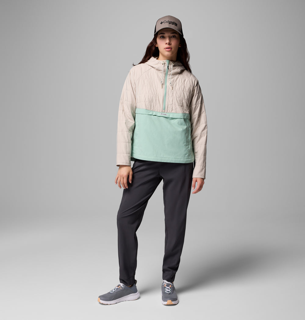 אדם לובש מעיל קולומביה ישראל PFG Uncharted II Insulated Anorak בצבעי בז' וירוק מנטה, מכנסיים כהים, נעלי ספורט אפורות וכובע אפור, בעודו עומד על רקע אפור אחיד.