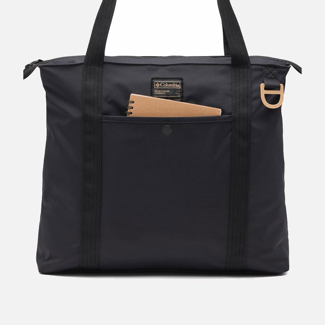 תיק "קולומביה ישראל" בצבע שחור מדגם "Cottonwood Creek Tote", עם שתי ידיות, רוכסן עליון, כיס חיצוני שבו מונח מחברת ספירלה חומה, ולולאה מפלסטיק בצבע בז' על אחת הידיות.