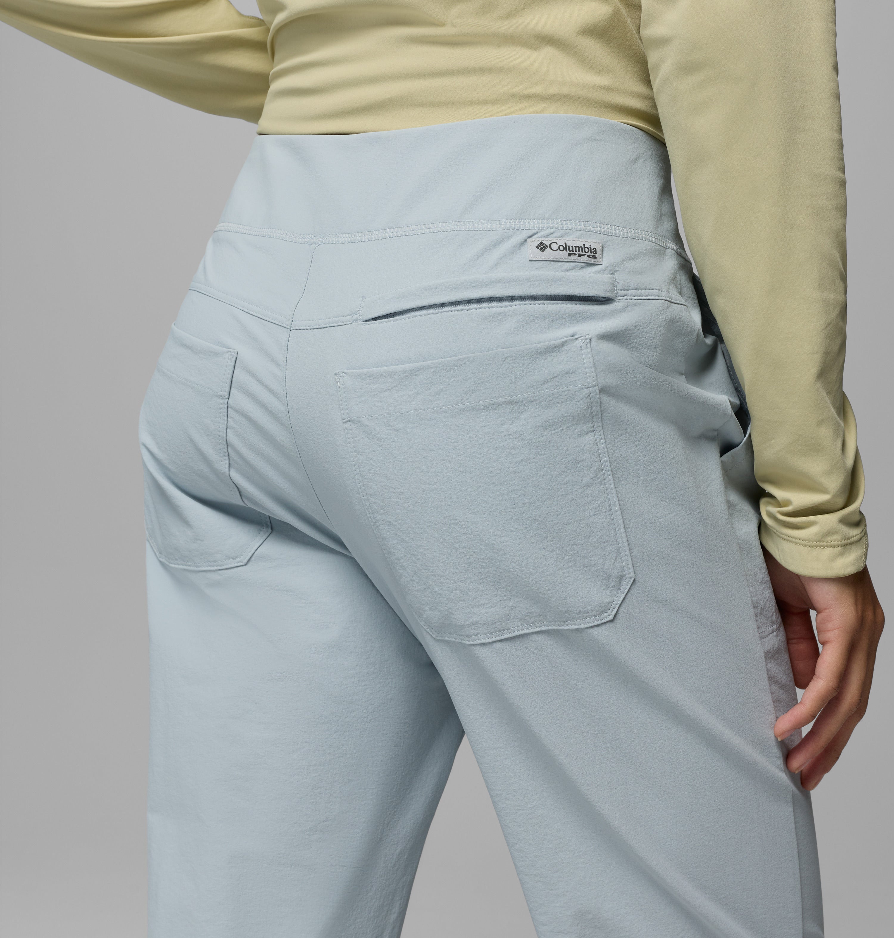 נראה אדם מאחור, לבוש במכנסי "Wild Cast Pant" של קולומביה ישראל בצבע תכלת ובחולצה ארוכת שרוולים בצבע צהוב בהיר, כאשר כיסי המכנסיים ולוגו קולומביה נראים בבירור.