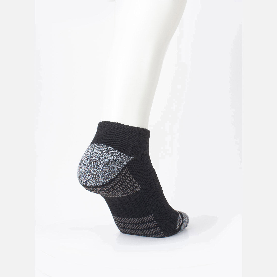רגל של בובה מציגה גרביים מדגם "ColumbiaIL Fashion No Show Half Cush 2pk" בצבעים שחור ואפור על רקע לבן, עם חלקים מרקמים בצבע אפור בעקב ובקצה כף הרגל, המעניקים נוחות וסגנון משופרים.