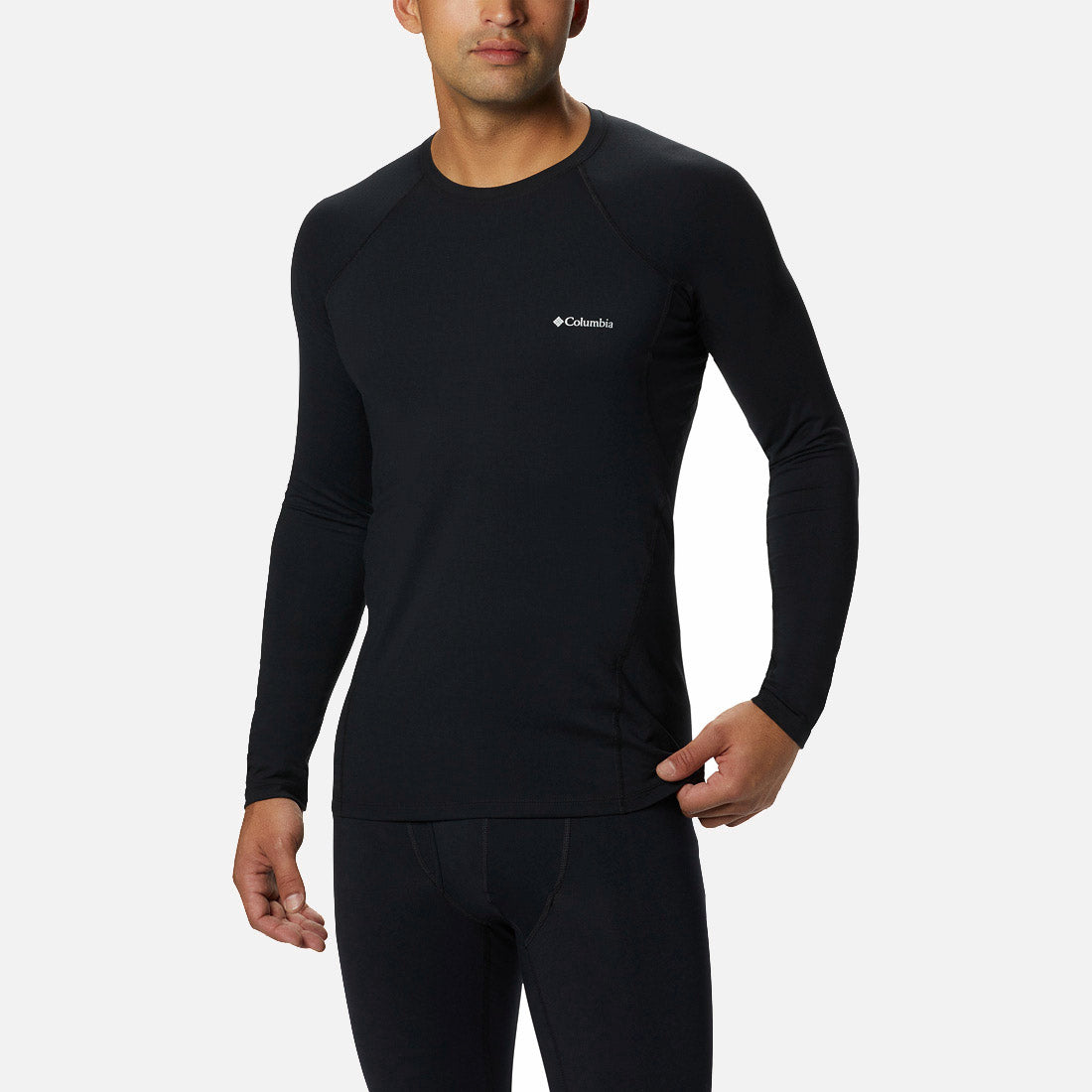 אדם לבוש בחולצת קולומביה IL Midweight Stretch ארוכת שרוולים בצבע שחור, עם מכנסיים שחורים תואמים, עומד על רקע לבן חלק.