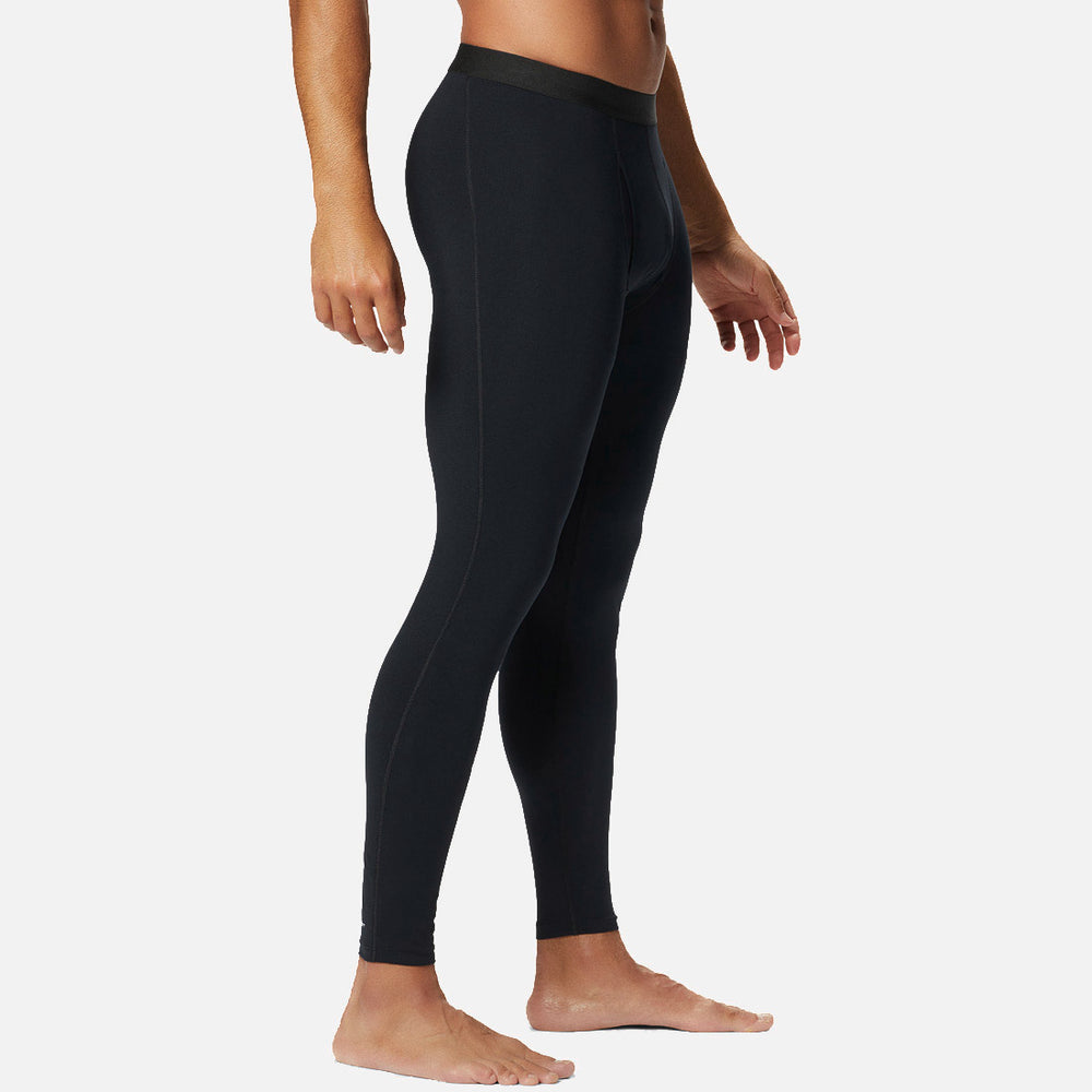 אדם עומד יחף, לבוש במכנסי טייץ "Midweight Stretch Baselayer" של המותג ColumbiaIL, מצולם מהצד על רקע לבן.