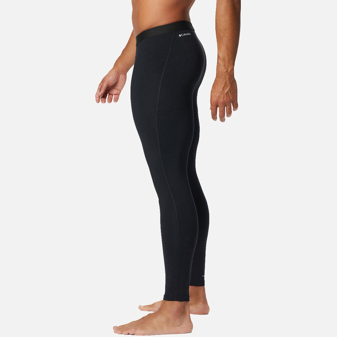 גבר עומד בפרופיל, יחף, לבוש במכנסי טייץ "ColumbiaIL Midweight Stretch Baselayer", על רקע לבן חלק.
