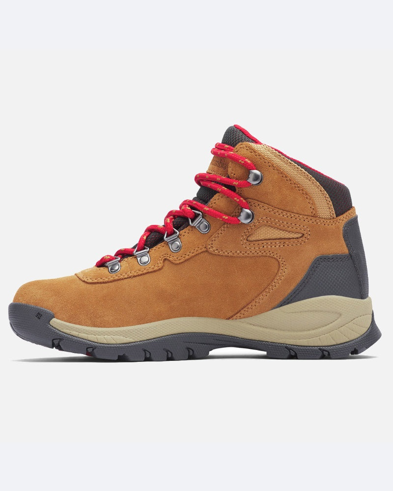 מגף ה-Newton Ridge Plus Waterproof של ColumbiaIL כולל זמש בצבע חום בהיר, שרוכים אדומים, לולאות מתכת, נגיעות אפורות בעקב ובקצה הנעל, וסוליה שחורה ועמידה מגומי. מוצג בפרופיל צדדי על רקע בהיר אחיד. מבנה אטום למים להבטחת עמידות.