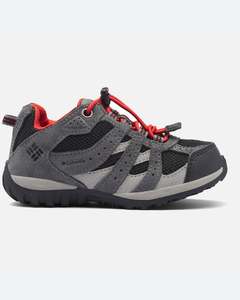 דגם "ColumbiaIL Youth Redmond Waterproof" הוא נעל ספורט בצבעי אפור ושחור עם נגיעות אדומות, סוליה עמידה, אוורור מרשת ומערכת שרוכים עם אבזם אדום — אידיאלית לטיולים ולפעילויות בשטח עבור בני נוער.