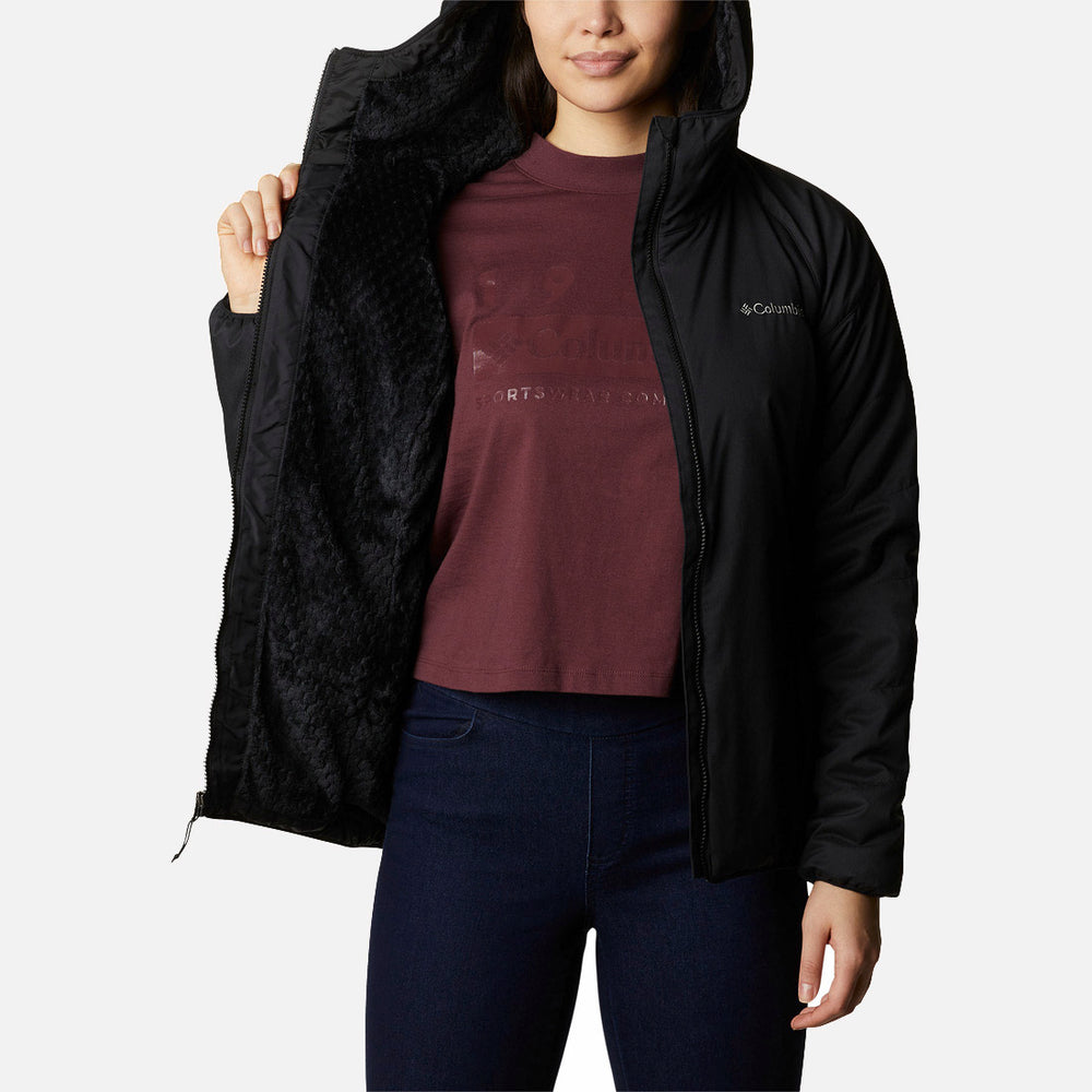 האדם לובש מעיל Softshell שחור מדגם Kruser Ridge II של ColumbiaIL, שרוכסנו פתוח בצד שמאל כדי להראות את הבטנה הרכה, ומשלב אותו עם חולצת טי בורדו וג'ינס כהה על רקע לבן חלק.