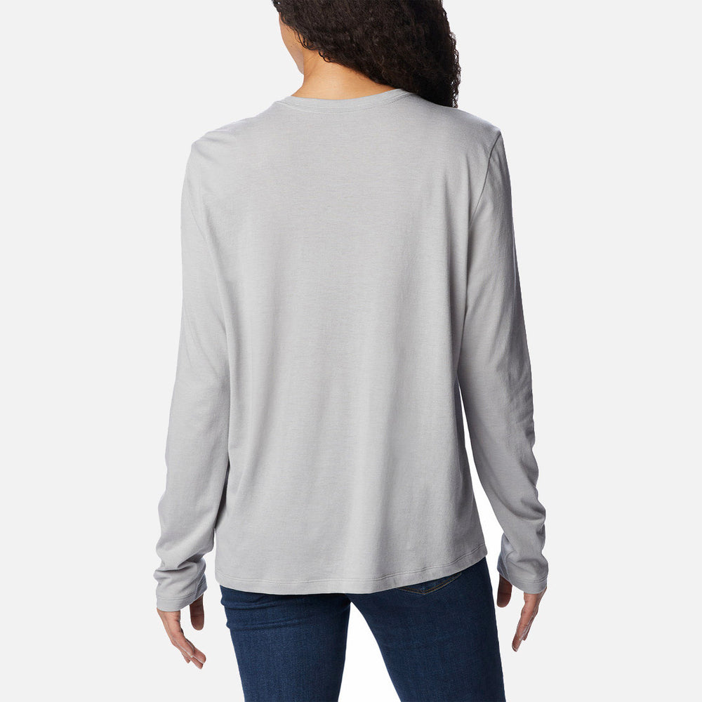 אדם בעל שיער ארוך ומתולתל, לבוש בחולצת Columbia Trek Relaxed L/S T מבית columbiaIL ובג'ינס כחול כהה, מצולם מאחור על רקע לבן חלק.