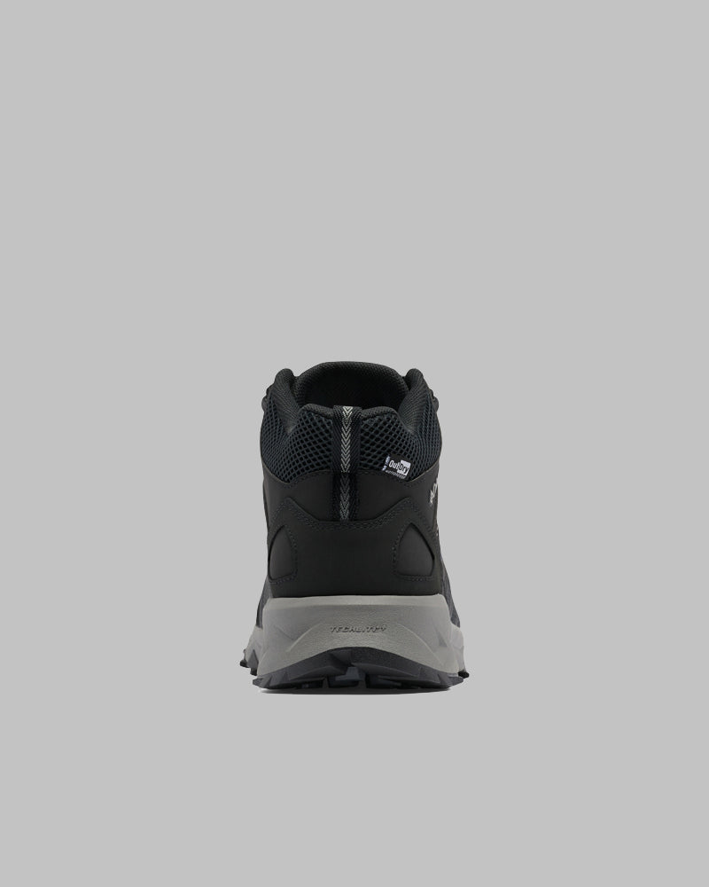 ה-Peakfreak II Mid Outdry מבית columbiaIL מוצג במבט מאחור על רקע אפור, תוך הדגשת פרטי העקב, הסוליה והחלק העליון מרשת — מושלם למי שמחפש נעלי שטח עמידות.