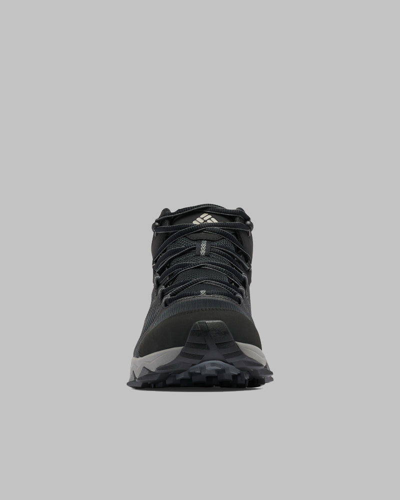 מבט מלפנים על נעל טיולים מדגם Peakfreak II Mid Outdry של ColumbiaIL בצבעים שחור ואפור, עם שרוכים גלויים, חלק עליון מרשת וסוליה מחוספסת עם דפוס על רקע אפור בהיר אחיד — אידיאלית לחובבי הנעלה לפעילויות בשטח.