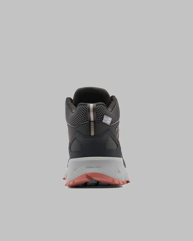 מבט מאחור על נעל ה-Peakfreak II Mid Outdry W של ColumbiaIL בצבעים כהים, עם גפה מרשת, נגיעות של אפור וורוד, וסוליה מחוספסת על רקע אפור בהיר — אידיאלית להרפתקאות בחיק הטבע לנשים.