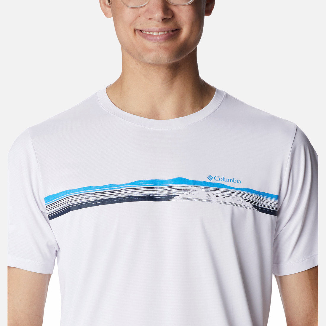 אדם מחייך המרכיב משקפיים מדגמן את חולצת ה-Columbia Hike Graphic S/S T מבית columbiaIL, חולצת טי לבנה עם שרוולים קצרים המעוטרת בפסים מופשטים בכחול ובשחור — אידיאלית לטיולים רגליים או להרפתקאות בטבע.