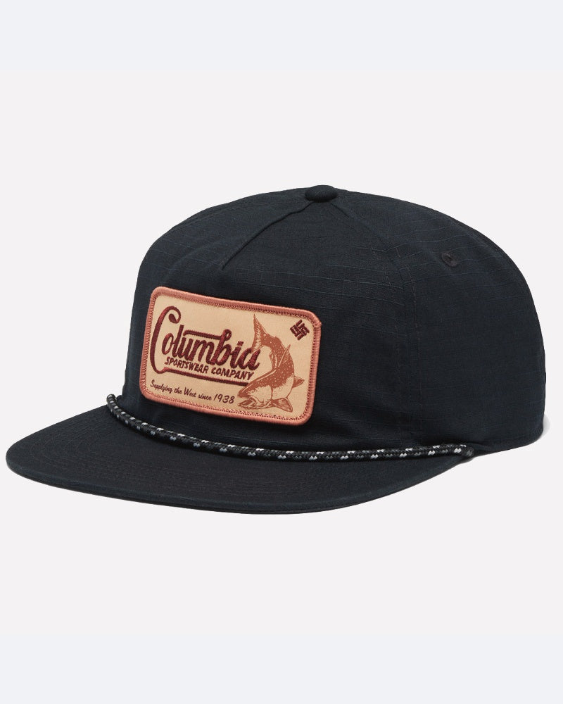 כובע "Ratchet Strap Snap Back" שחור של המותג ColumbiaIL, עם שוליים שטוחים, חוט קלוע מעל השוליים, ותווית בצבע חום בהיר בחזית הכובע, עליה מופיעים שם המותג, איור של דג והכיתוב "keeping the bite since 1938". הכובע מצויד במנגנון כוונון אחורי עם לחצן.