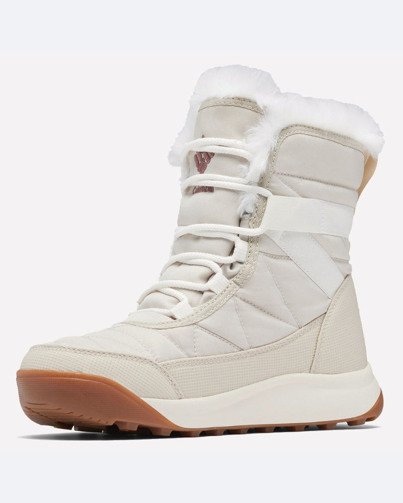 ה-ColumbiaIL Minx Shorty IV הוא מגף חורף בצבע בז' עם שרוכים לבנים, גימור מפרווה סינתטית, תפרים מרופדים וסוליה מגומי בצבע חום בהיר, המיועד למזג אוויר קר.