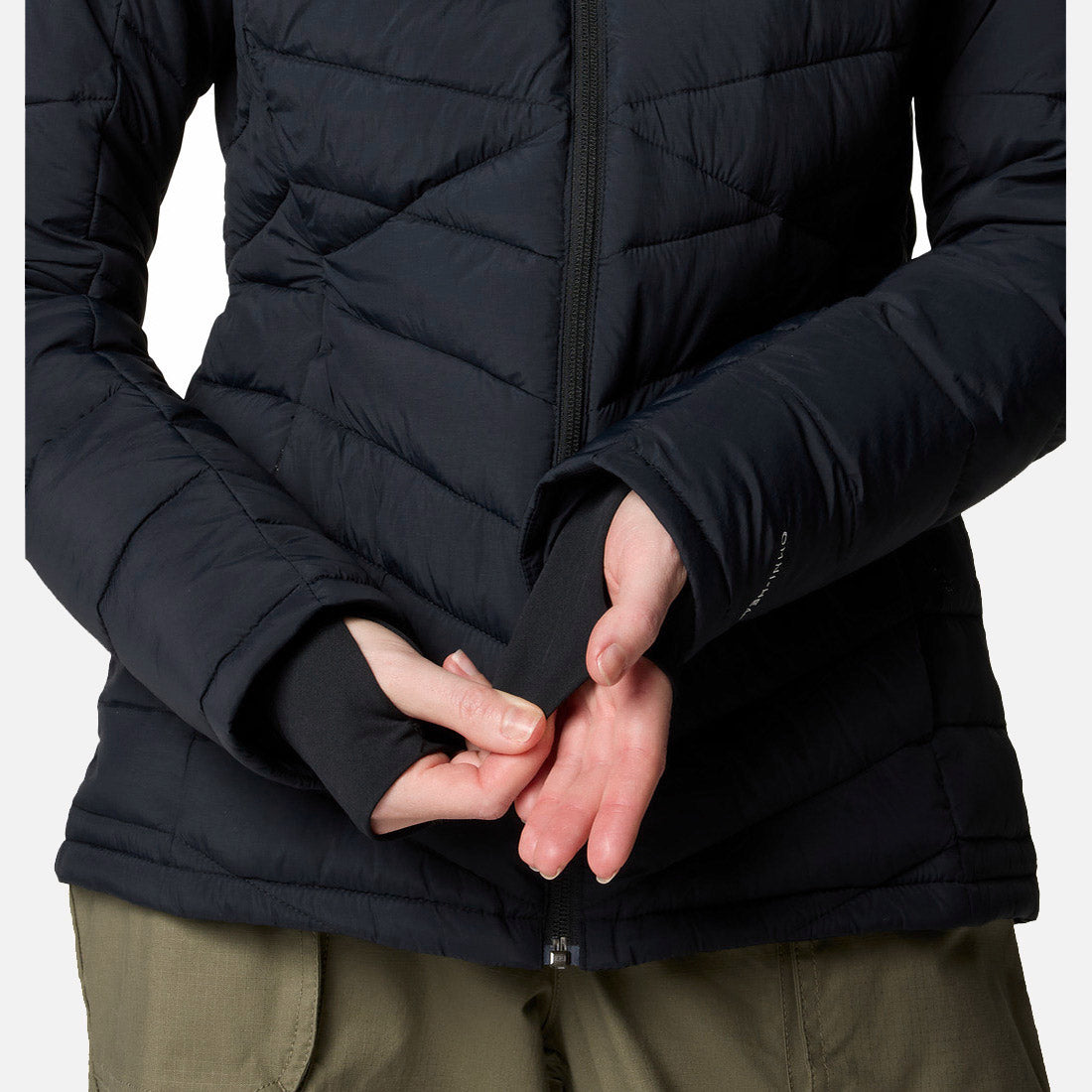 אדם הלובש סווטשירט שחור מדגם "Joy Peak II Full Zip" של המותג "ColumbiaIL" ומכנסיים בצבע ירוק זית, מסדר את שולי השרוול עם החור לאגודל בגובה המותניים, כשפניו אינן נראות.