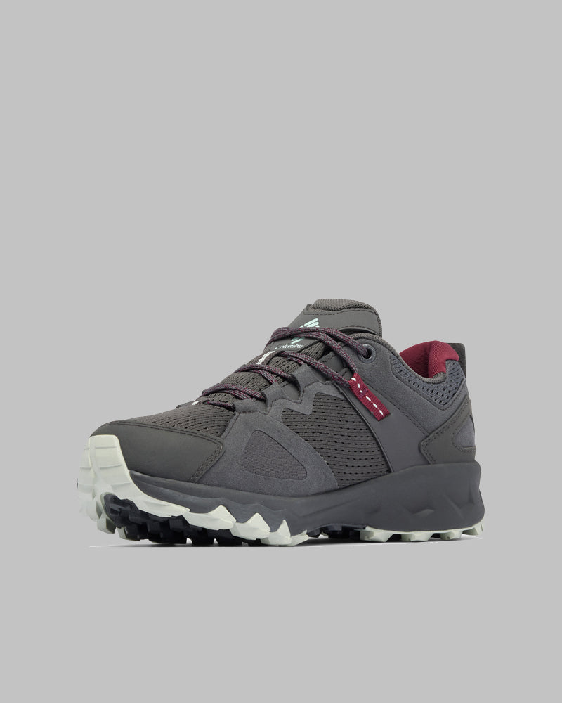 דגם Peakfreak Hera Outdry מבית קולומביה ישראל הוא נעל טיולים אפורה עם סוליה מרקמת בצבעי לבן ושחור, שרוכים סגולים ואלמנטים אדומים, המוצגת על רקע אפור אחיד.