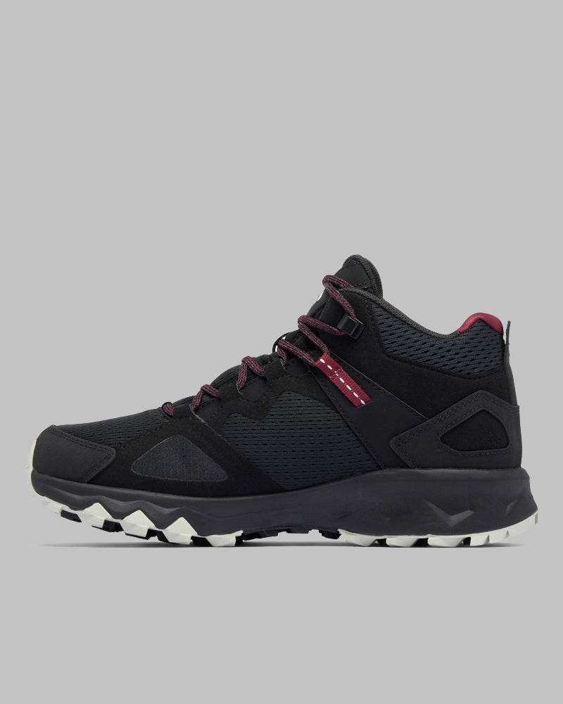 דגם ה-Peakfreak Hera Mid Outdry של קולומביה ישראל, נעל טיולים שחורה בגובה בינוני עם נגיעות בצבע אדום כהה, לוחות רשת וסוליה לבנה ומחוספסת, מוצגת בפרופיל על רקע אפור אחיד.