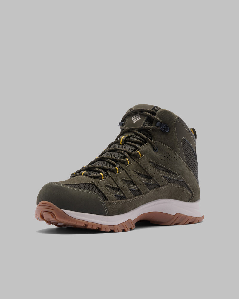 בתמונה נראית נעל טיולים בודדת מדגם Crestwood Mid Waterproof מבית קולומביה ישראל, בצבע ירוק זית עם שרוכים שחורים וצהובים, סוליה אמצעית לבנה וסוליה חיצונית חומה ומחוספסת, על רקע אפור אחיד.
