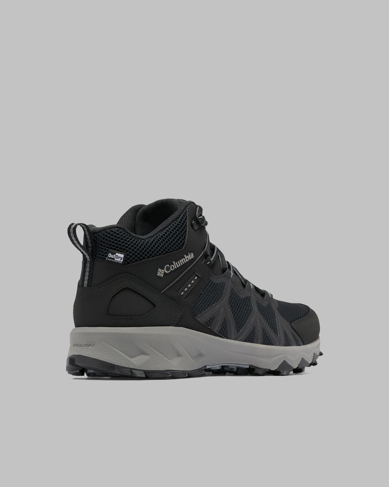 מגף טיולים לגברים מדגם Columbia IL Peakfreak II Mid Outdry M בצבעי שחור ואפור, עם לוחות רשת, סוליה עמידה ועיצוב עם שרוכים, מוצג מאחור משמאל על רקע אפור אחיד.