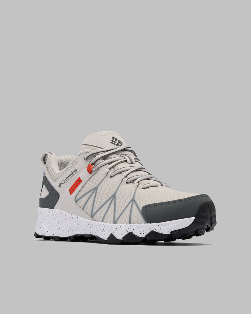נעל ספורט Peakfreak II Outdry בצבעי אפור בהיר ולבן מבית columbiaIL, עם נגיעות בצבע אפור כהה, סוליה לבנה מנוקדת עם דפוס שחור ופרטים אדומים. לוגו Columbia מופיע בצד ובלשון הנעל. מוצגת על רקע אפור אחיד.