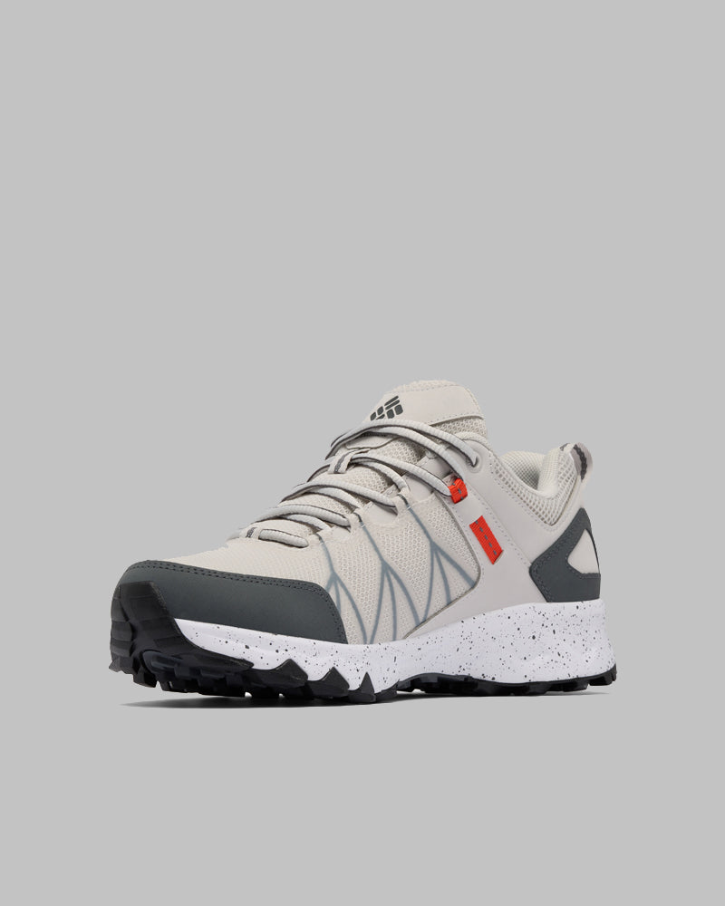 ה-Peakfreak II Outdry של ColumbiaIL הוא נעל ספורט בצבעי בז' ואפור, עם שרוכים אפורים בהירים, סוליה לבנה מנוקדת, דפוס שחור על הסוליה ואלמנטים כתומים עדינים, המוצגת על רקע אפור בהיר.