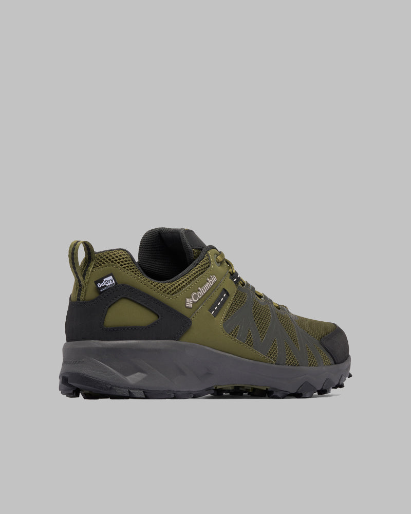 נעל טיולים מדגם Peakfreak II Outdry של ColumbiaIL בצבעי ירוק ושחור, עם סוליה מחוספסת, גפה מרשת וחומר סינתטי, ולולאה בעקב, מוצגת על רקע אפור אחיד.
