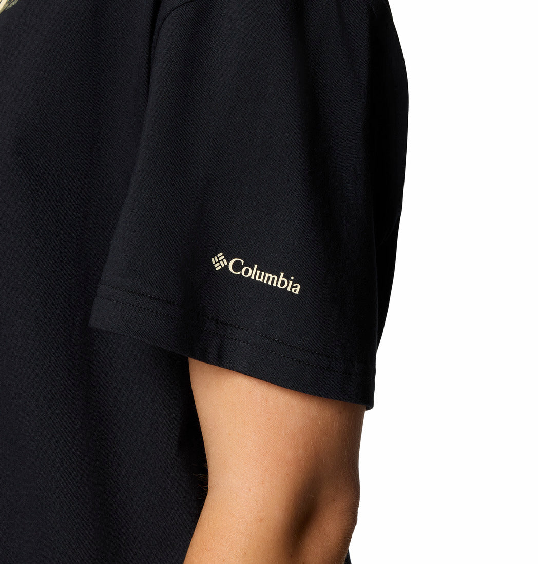תקריב של זרוע עליונה בחולצת ColumbiaIL Graphic Relaxed Crop Short Sleeve שחורה, עם לוגו Columbia לבן על השרוול. הסגנון הקצר והרפוי יוצר ניגוד עם הרקע הלבן הפשוט.