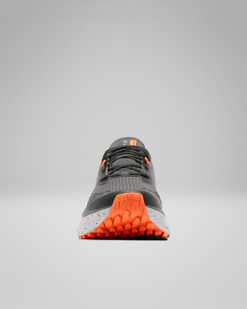 נעל הריצה "Konos Trillium Atr M" של קולומביה ישראל, בצבעים שחור ואפור, כוללת סוליה ופרטים בצבע כתום בוהק, שרוכים שחורים וסוליה אמצעית מנוקדת, והיא מוצגת במבט מלפנים על רקע אפור אחיד.