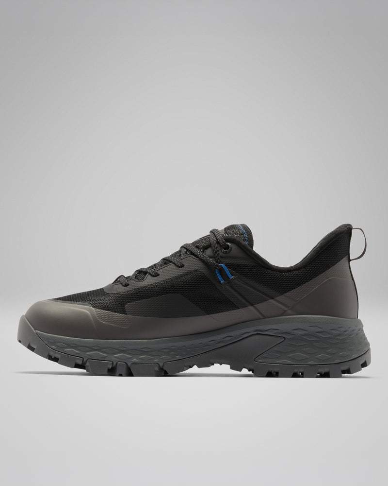 נעל הריצה בשטח Tellurix Titanium Outdry של קולומביה ישראל מוצגת בצבעים שחור ואפור כהה, עם חלק עליון מרשת מרקמית, סוליה יציבה ודפוס צמיג מחוספס בפרופיל הצדדי על רקע אפור בהיר — אידיאלית לשימוש אמין בפעילויות חוץ.