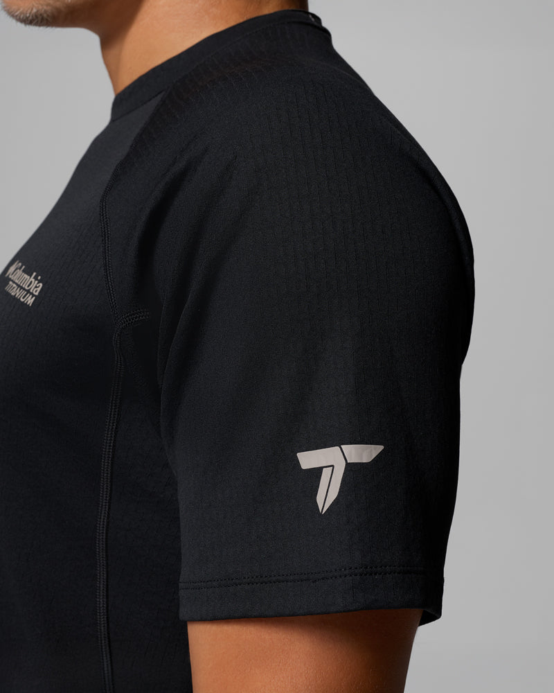 בתמונה מקרוב מהצד נראה אדם הלובש את חולצת ה-Driventure Short Sleeve Shirt מבית קולומביה ישראל, חולצת ספורט גברית בצבע שחור עם לוגו של קולומביה על החזה ולוגו לבן קטן על השרוול.