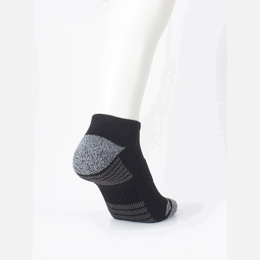 רגל של בובה מציגה גרביים מדגם "ColumbiaIL Fashion No Show Half Cush 2pk" בצבעים שחור ואפור על רקע לבן, עם חלקים מרקמים בצבע אפור בעקב ובקצה כף הרגל, המעניקים נוחות וסגנון משופרים.